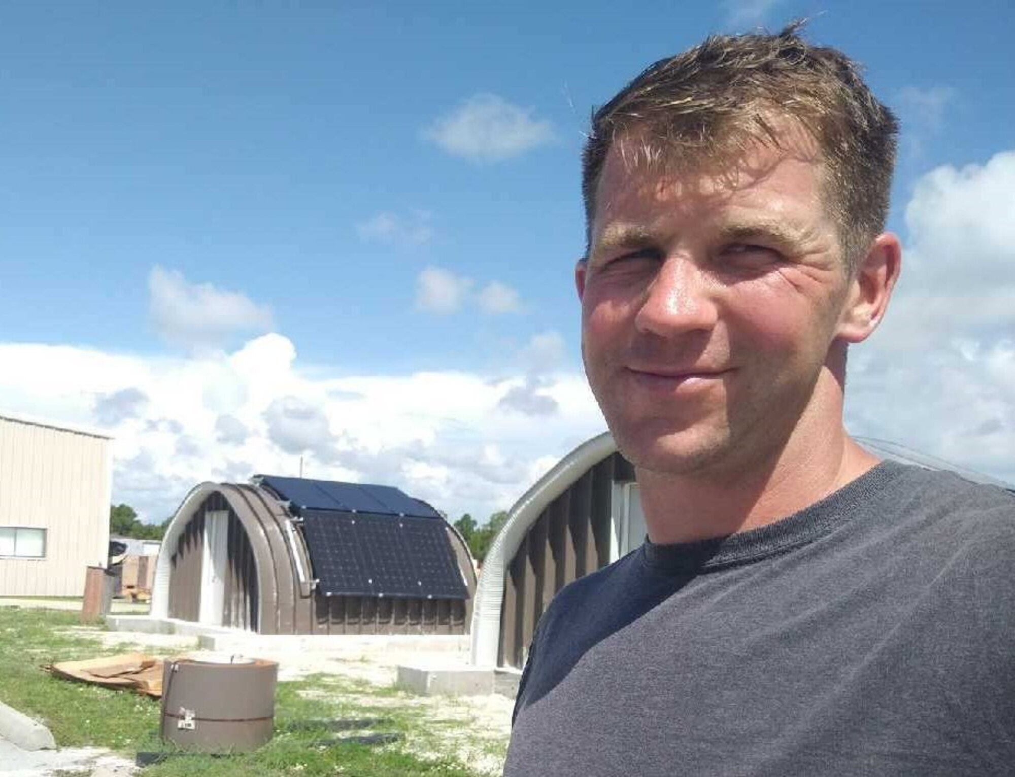 Man stands near rigid metal structure with solar panel system mounted on its side.