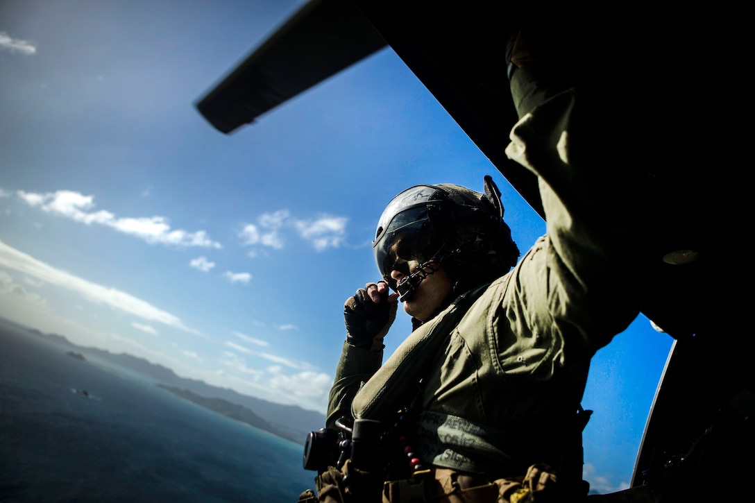 A Marine looks out the door of a UH-1N Huey helicopter.