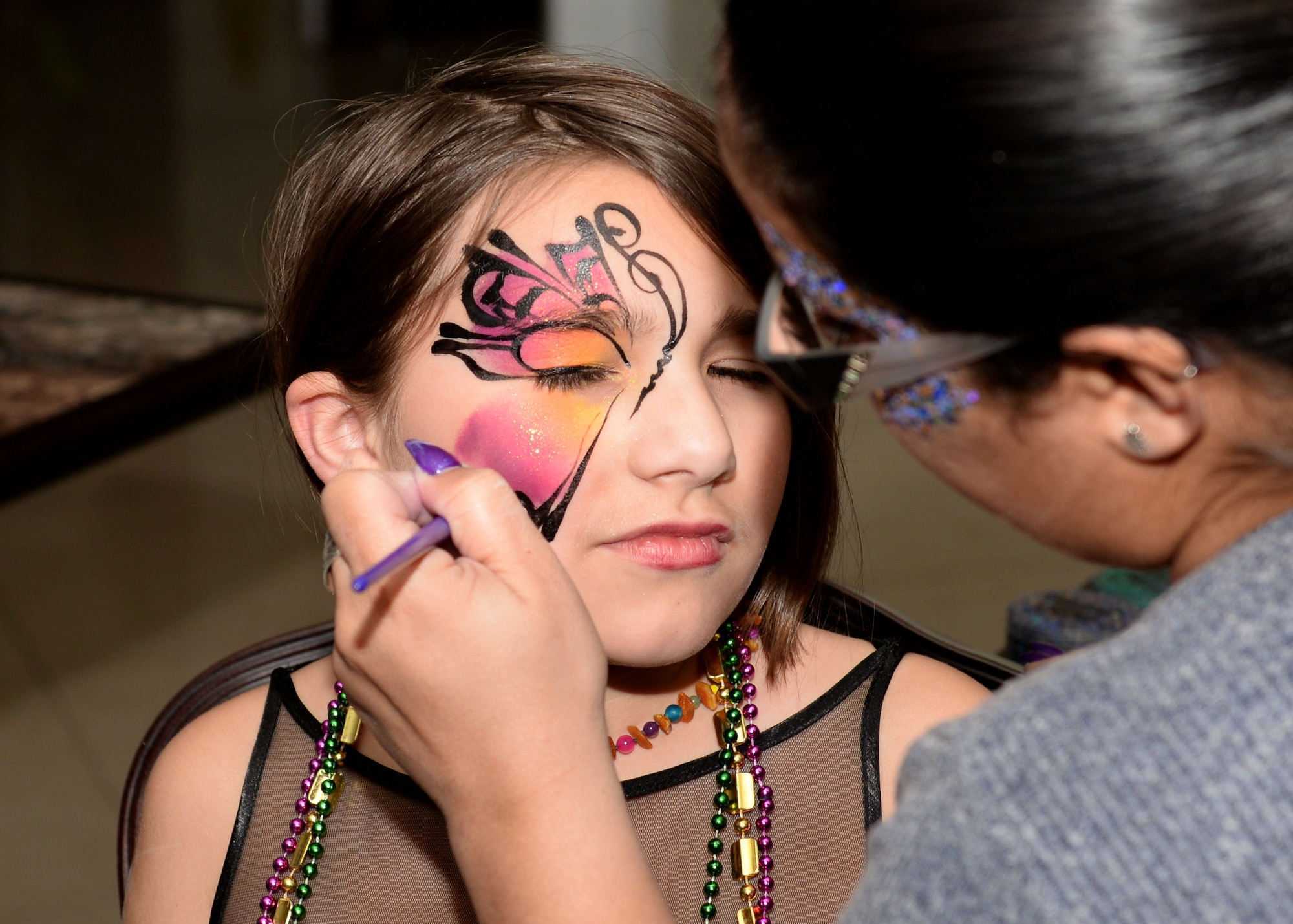 Laura Amaya, age 9, daughter of U.S. Navy Boatswain's Mate Chief Petty Officer Diedra Amaya, Cargo Handling Battalion 10, gets a butterfly painted on her face during the Mardi Gras celebration at Joint Base Langley-Eustis, Va., Feb. 9, 2018. Activities at the Mardi Gras celebration also included a fortune teller, casino games, a juggler and live music. (U.S. Air Force photo by Airman 1st Class Monica Roybal)