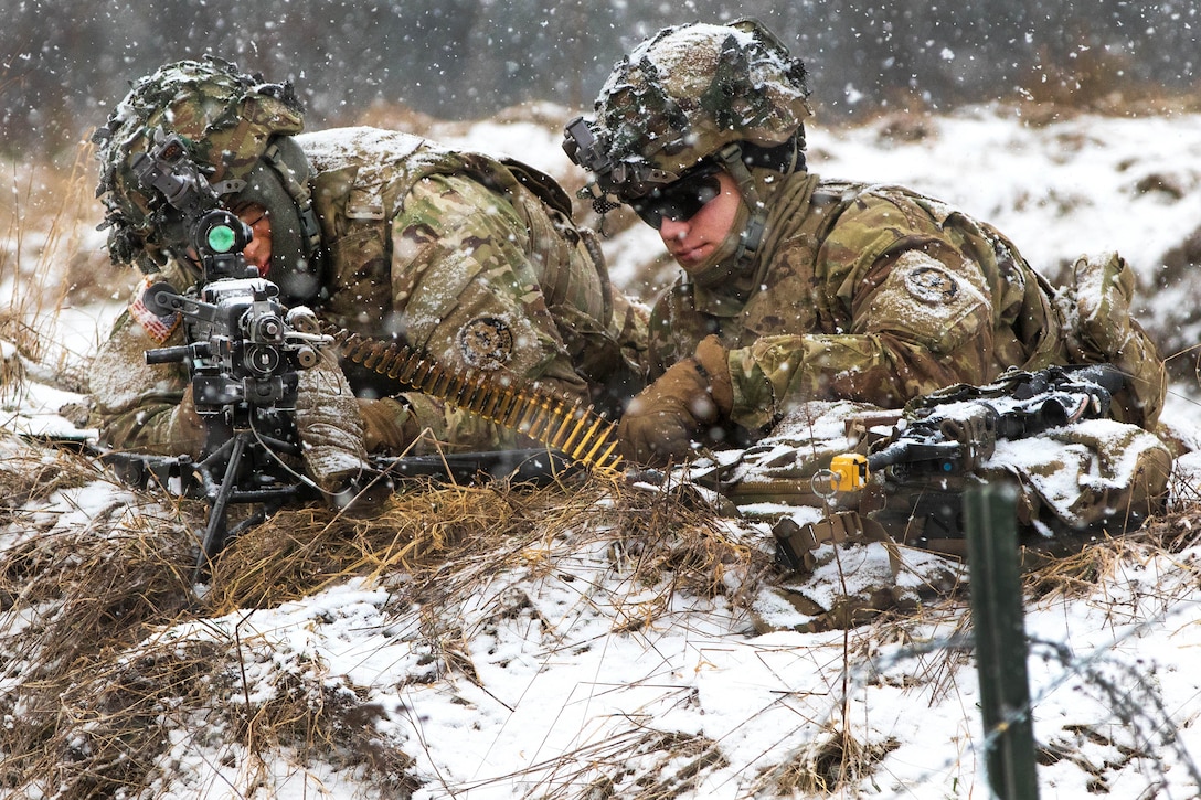 A soldier fires his machine gun at opposing forces while providing security from their defensive position.