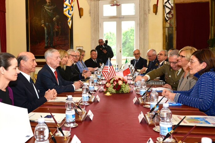 Defense Secretary James N. Mattis sits at a long table with other officials across from his Italian counterpart.