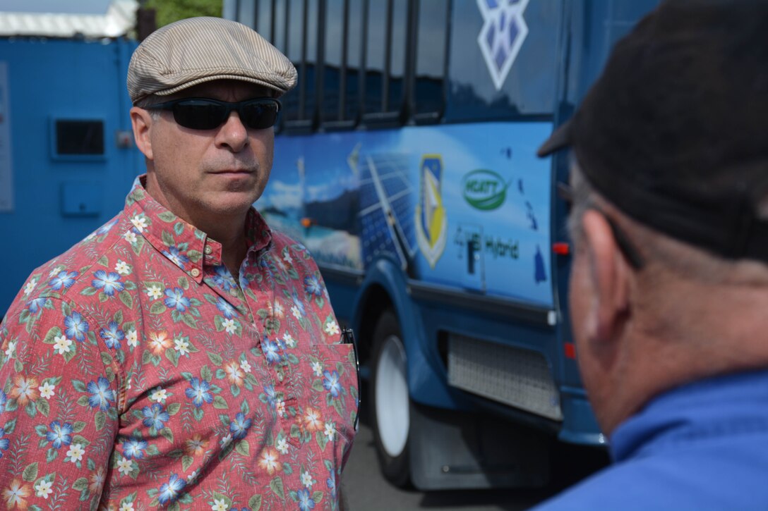 Man listens to another man speak in front of a hydrogen-powered bus