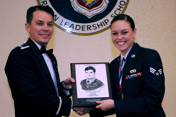 Col. Jeffrey Nelson, left, 628th Air Base Wing commander presents Senior Airman Allyson Walker-Cramer,628th Civil Engineer Squadron member, a plaque for earning the John L. Levitow Award during the class 18-B Airman Leadership School Graduation at the Charleston Club here Feb. 08, 2018. The Levitow Award is the highest honor awarded to an ALS graduate and is given to the Airman who displays the highest level of leadership qualities during the course. ALS is a five-week course encompassing lessons in the principles of supervision and management, the importance of communication and military professionalism.