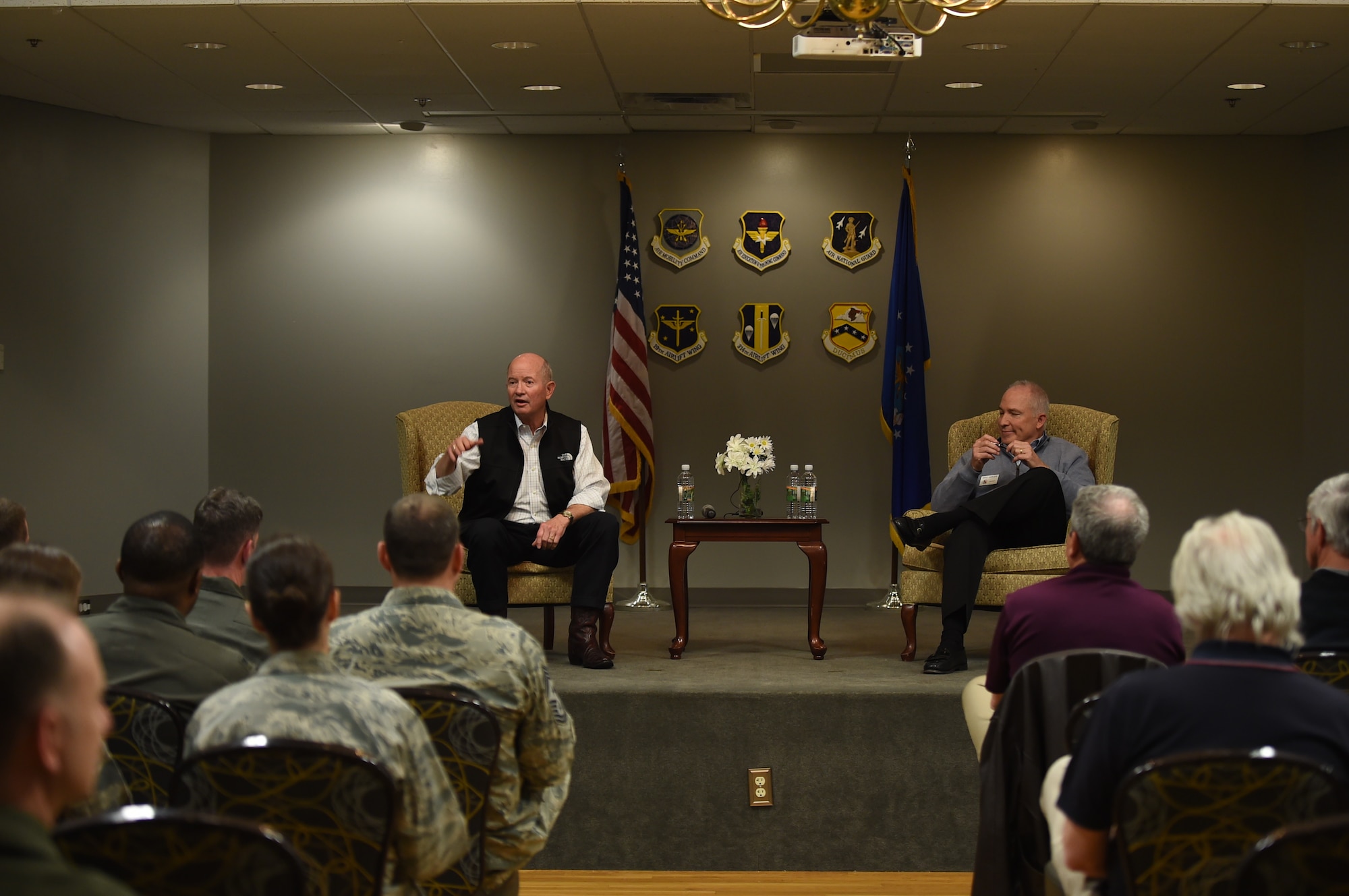Two retired military men sit on stage.
