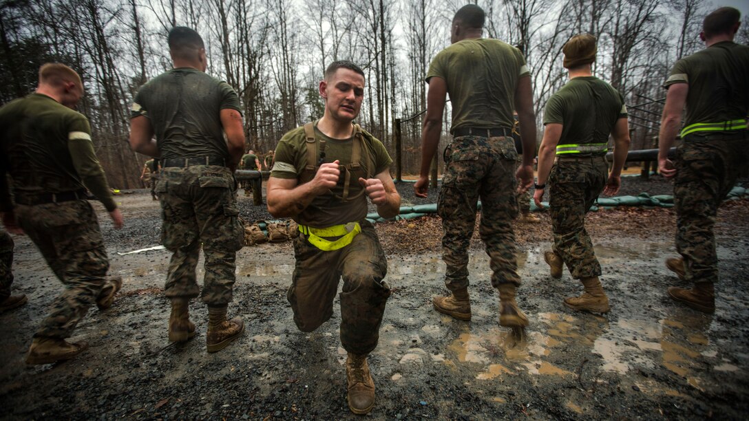 A Marine lunges outside while five others stand behind him facing the reverse direction.