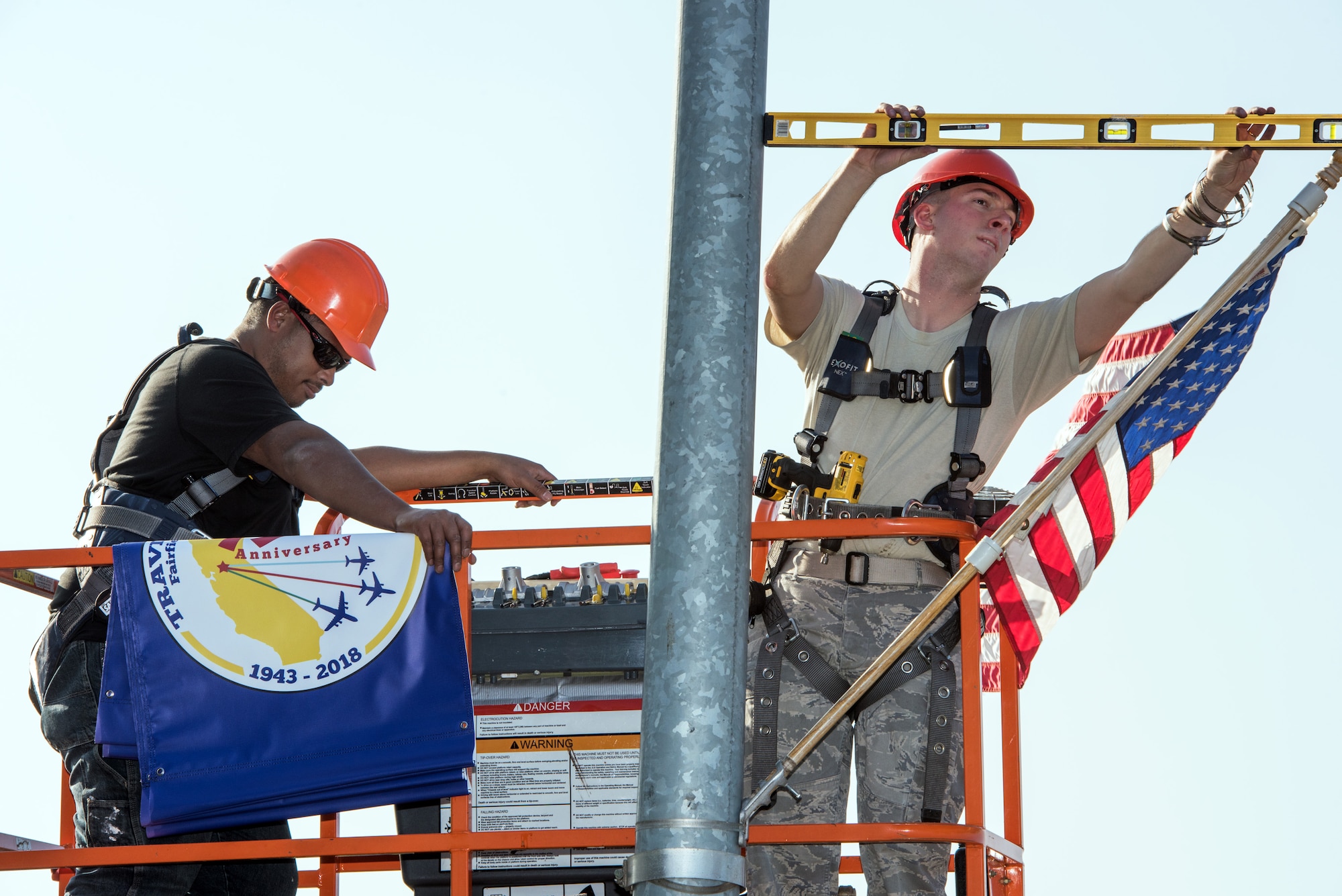 Members from the 60th Civil Engineer Squadron attach the 75th Anniversary banner to a light post at Travis Air Force Base, Calif., Feb. 7, 2018. For the past 75 years, Travis has been a focal point for the world as a power projection platform for the U.S. armed forces in the Pacific theater. (U.S. Air Force photo by Louis Briscese)
