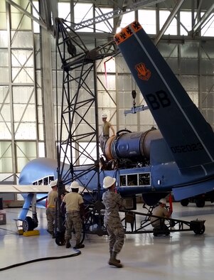 Airmen from the 12th Aircraft Maintenance Unit hoist an engine into an RQ-4 Global Hawk Jan. 25, 2018, at Edwards Air Force Base, California. The RQ-4 and 12th AMU Airmen recently returned to Beale after a major refurbishment was performed. The Global Hawk is a high-altitude, long-endurance, remotely piloted aircraft with an integrated sensor suite that provides global all-weather, day or night intelligence, surveillance and reconnaissance capability. (U.S. Air Force photo/Master Sgt. Wesley Sullivan)