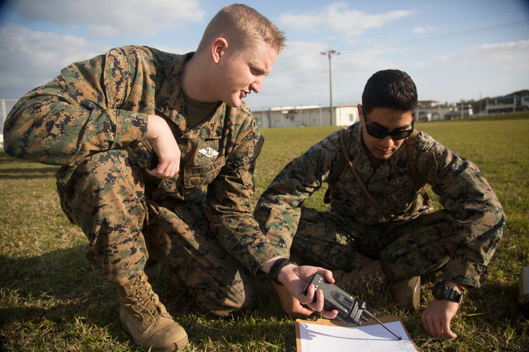 Petty Officer 3rd Class Tyler Bailey and Seaman Luis Pompa, hospital corpsmen with Medical Skills Training Center, 3rd Medical Battalion, 3rd Marine Logistics Group review the training scenario for the en-route care training evolution Feb. 13, 2018 at Marine Corps Air Station Futenma, Okinawa, Japan. U.S. medical military members, including Army and Air Force personnel, simulated en-route care procedures, focusing on familiarizing and expanding joint interoperability of patient evacuation from the point of injury on the battlefield to advanced medical care at a Role Two field hospital. Bailey is a native of Abilene, Texas and Pompa is a native of Dallas, Texas. (U.S. Marine Corps photo by Lance Cpl. Isabella Ortega)
