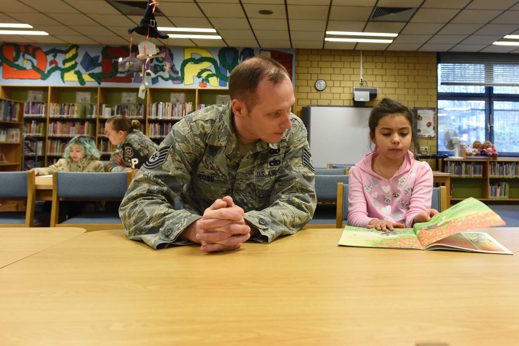 Tech. Sgt. Jere Ross, 86th Airlift Wing noncommissioned officer of resources and requirements, and Airman 1st Class Sarah Marcinko, 569th United States Forces Police Squadron security forces personnel, read with children on Feb. 6, 2018 at Vogelweh Elementary School on Vogelweh Military Complex, Germany. Children select a book based on their reading ability and then read to their military volunteer for up to 30 minutes at a time.