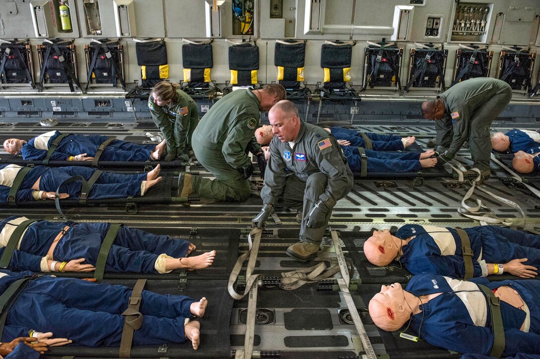 Airmen secure mock patients to litters before conducting an in-flight aeromedical evacuation training exercise.