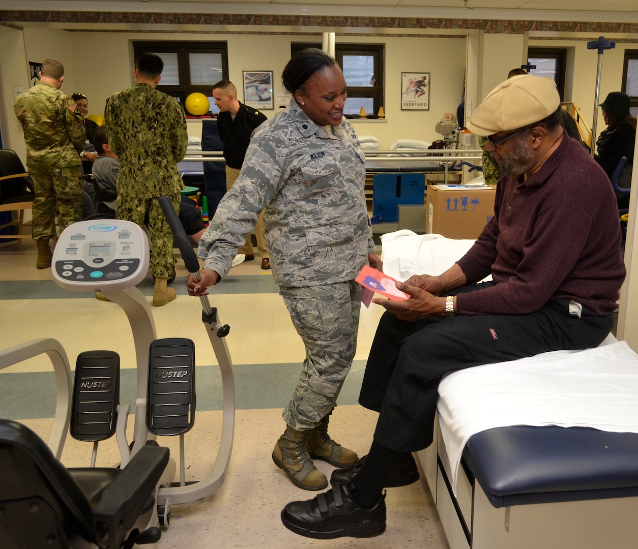 Air Force Lt. Col. Chiriga Wilson presents a thank you card to a patient receiving physical therapy at the Corporal Michael J. Crescenz Veterans Affairs Medical Center, Feb. 12, 2018 in Philadelphia.
