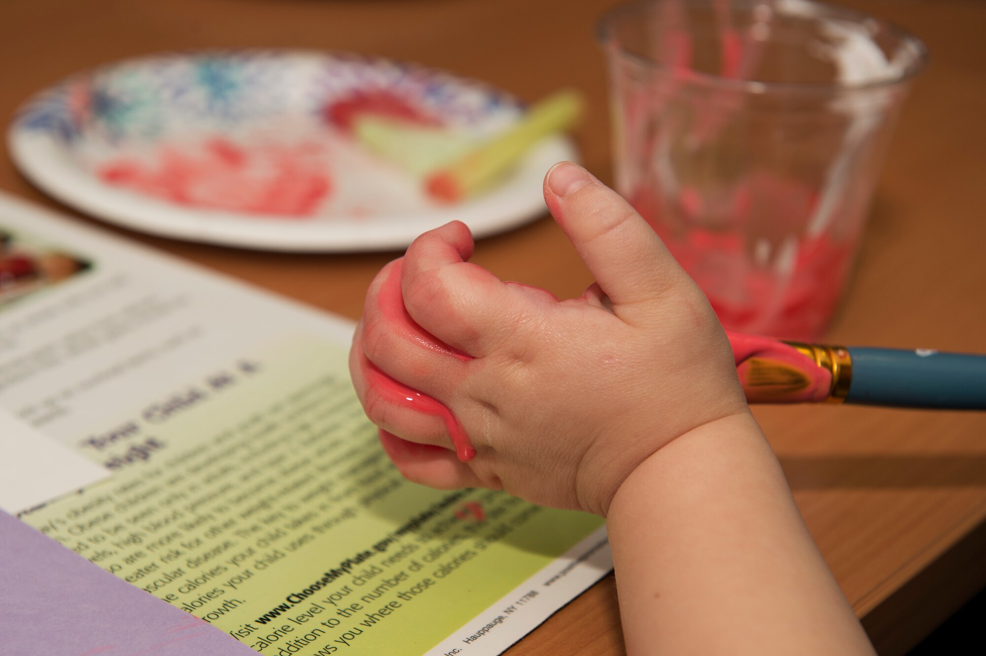 A child paints her hand Feb. 14, 2018 at the Fitness and Sports Center at Royal Air Force Lakenheath, England. The Women, Infants and Children Overseas program organizes kid-friendly activities for each of its monthly nutritional classes to engage and inspire its young attendees. (U.S. Air Force photo/Airman 1st Class Shanice Williams-Jones)