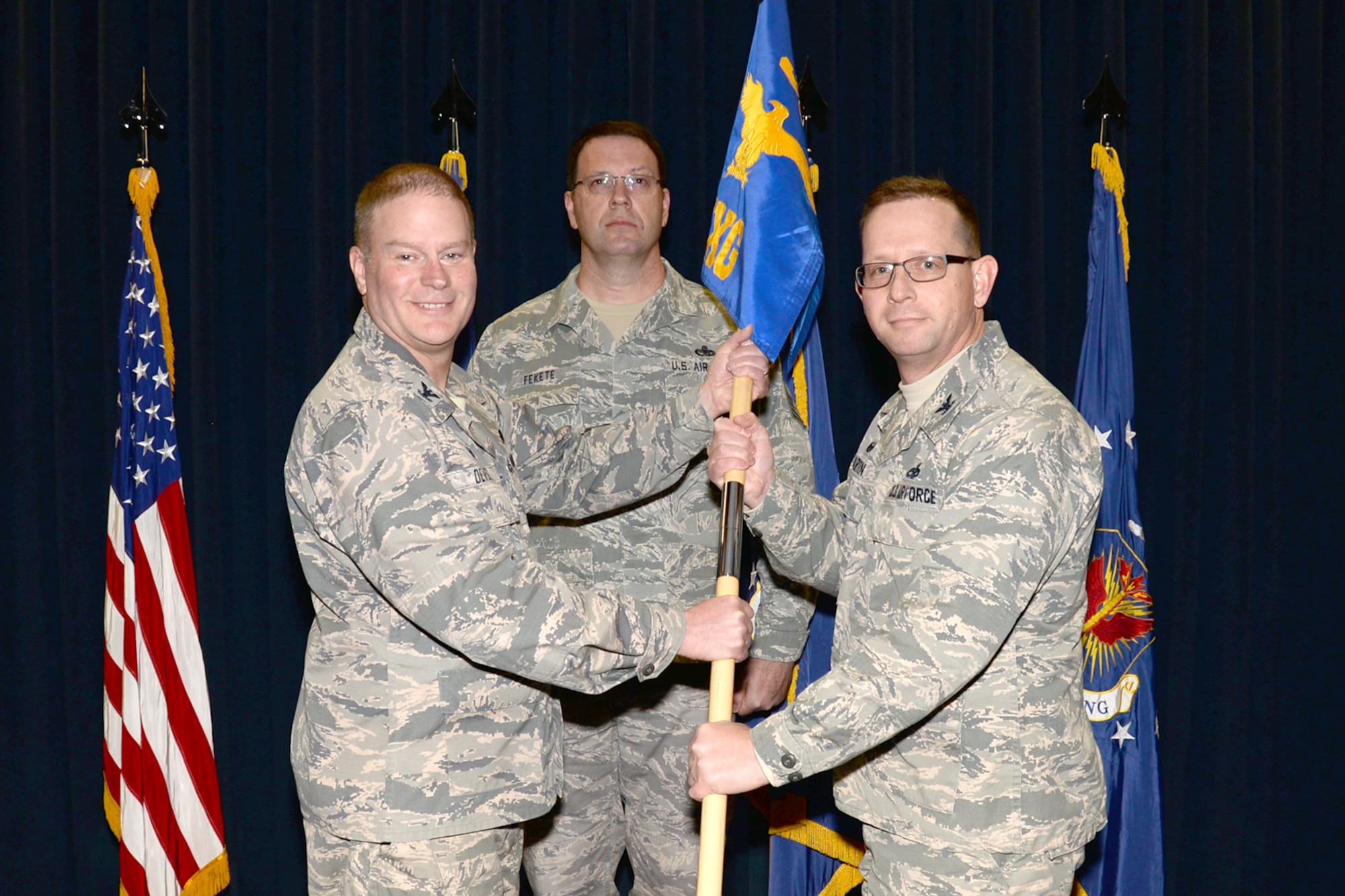 Col. James DeVere, 302nd Airlift Wing commander, passes the 302nd Maintenance Group guidon to the new group commander, Col. Jason Martin, at an assumption of command ceremony, Feb. 11, 2018, at Peterson Air Force Base, Colorado.