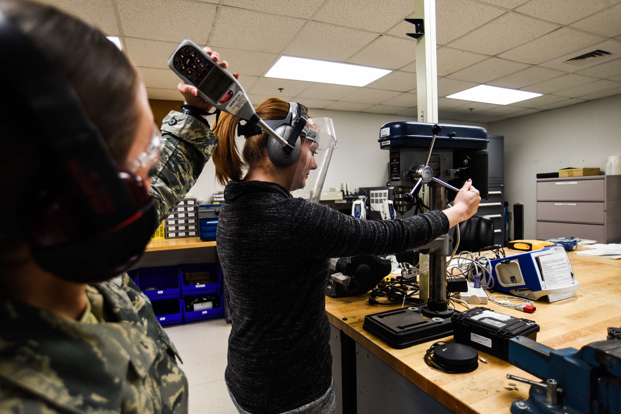 Airman 1st Class Kimberly Haggard, 90th Medical Group bioenvironmental engineer technician, measures the noise levels in a mechanical shop as a staff member works on the drill press Feb. 8, 2018 at F.E. Warren Air Force Base, Wyo. It is imperative the noise levels are checked when a new piece of machinery is brought into a shop to verify all Airmen have the proper equipment to protect their hearing, as well as other potential hazards.