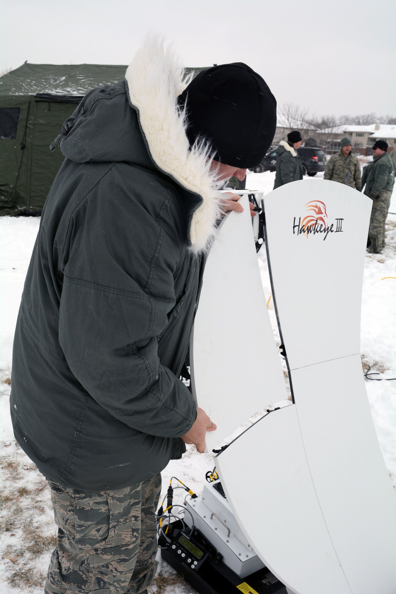 Staff Sgt. Cody Sachtjen, cyber transport systems specialist with the Air National Guard's 115th Fighter Wing, erects a data uplink satellite dish for the Joint Interoperability Site Communications Capability team's network and telephone systems during the State Interoperable Mobile Communications Exercise (SIMCOM) in Fitchburg, Wis., Feb 7, 2018. The annual SIMCOM exercise tests the interoperability of federal, state and local emergency communications agencies. (U.S. Air National Guard photo by Tech. Sgt. Mary Greenwood)