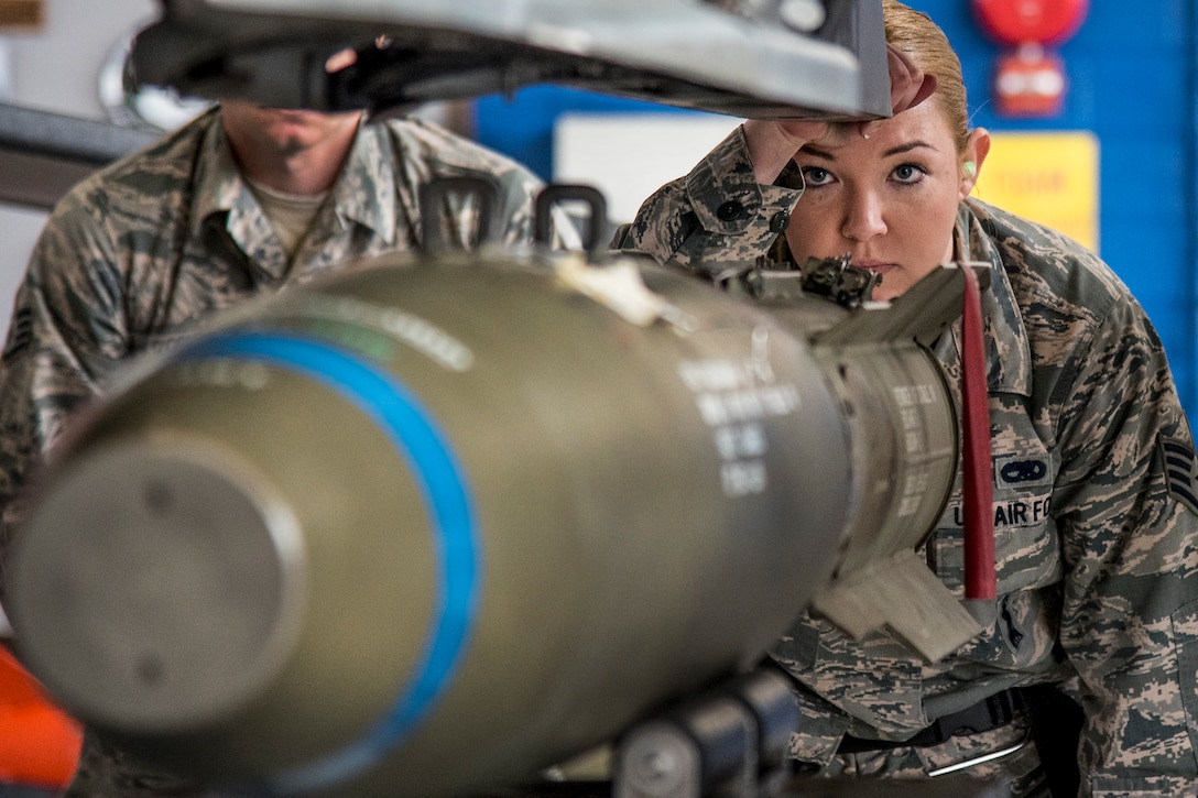 An airman watches as crews move an MK-82 into place.