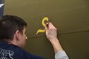 (01/25/2018) Museum restoration specialist Casey Simmons paints the letter 'S' for 'Sally' below the left waist gun position of the Boeing B-17F Memphis Belle as part of the aircraft restoration. Plans call for the aircraft to be placed on permanent public display in the WWII Gallery of the National Museum of the U.S. Air Force on May 17, 2018. (U.S. Air Force photo by Ken LaRock)