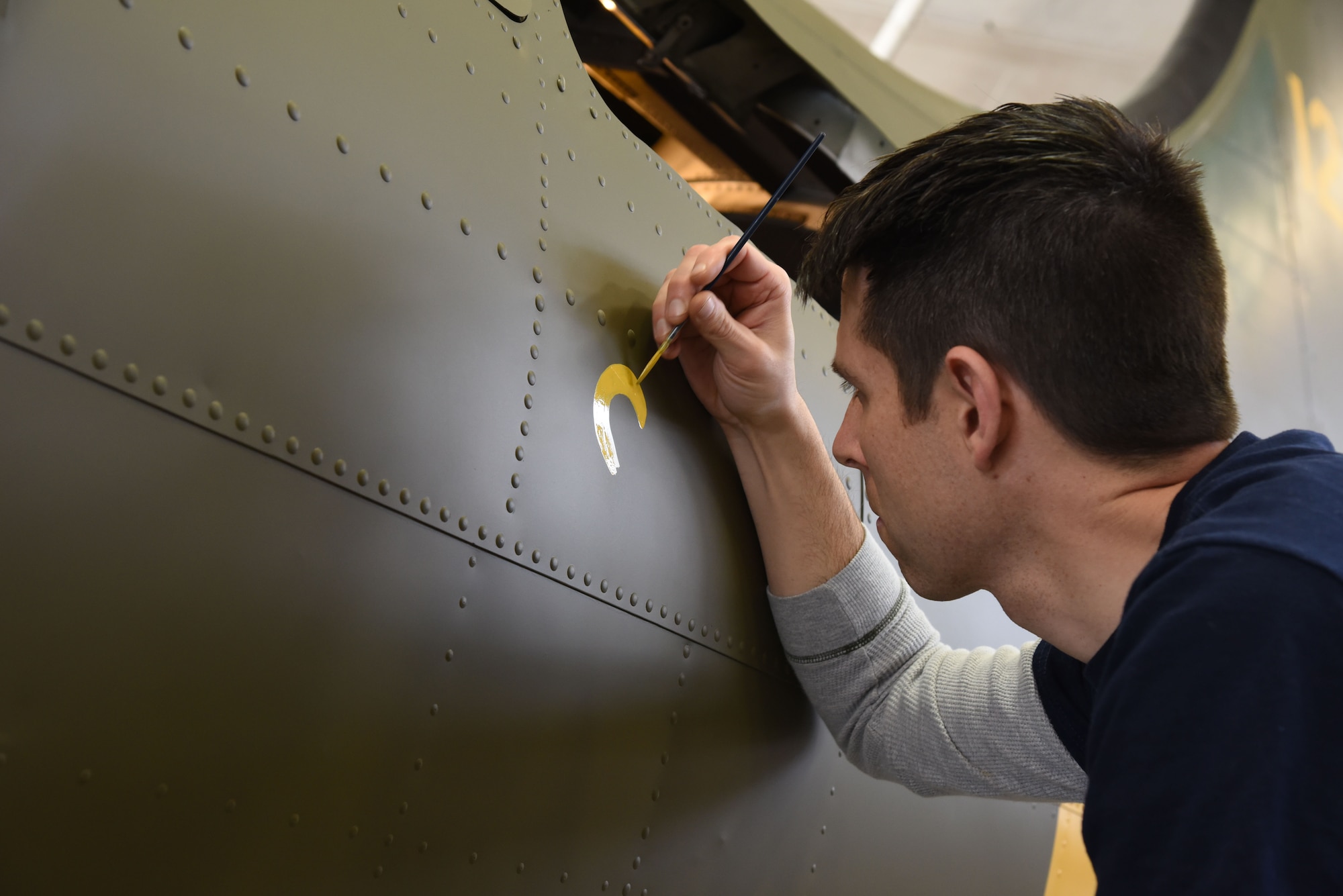 (01/25/2018) Museum restoration specialist Casey Simmons paints the letter 'S' for 'Sally' below the left waist gun position of the Boeing B-17F Memphis Belle as part of the aircraft restoration. Plans call for the aircraft to be placed on permanent public display in the WWII Gallery of the National Museum of the U.S. Air Force on May 17, 2018. (U.S. Air Force photo by Ken LaRock)