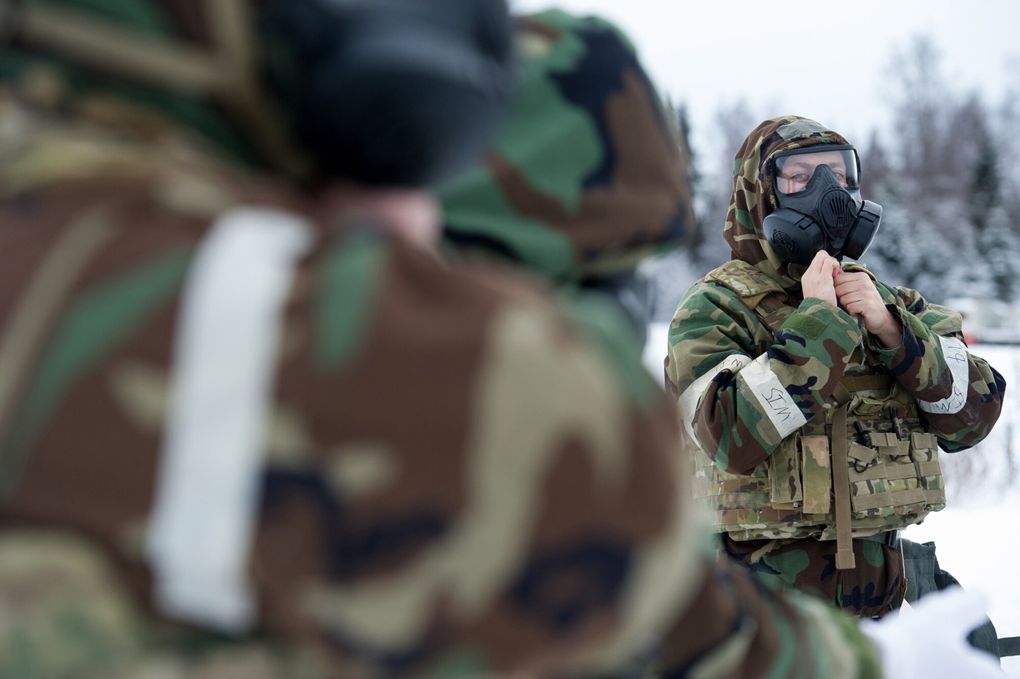 An Airman assigned to the 673d Civil Engineer Squadron, Explosives Ordinance Disposal Flight, adjusts his protective gear before a live-fire demolitions exercise in Mission Oriented Protective Posture 4 on Joint Base Elmendorf-Richardson, Alaska, Feb.14, 2018.  The Airmen were conducting EOD training in a simulated chemical weapons contaminated environment.