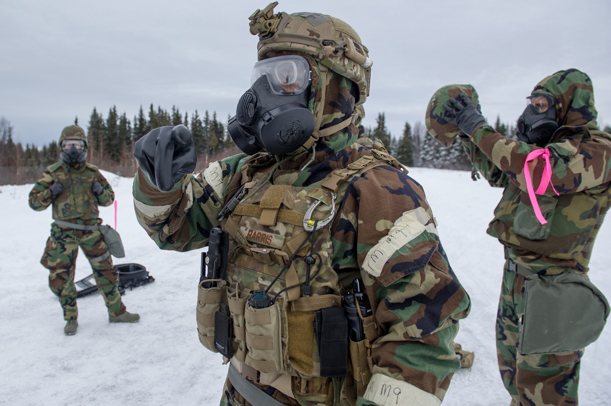 Air Force Staff Sgt. Joshua Harris, assigned to the 673d Civil Engineer Squadron, Explosives Ordinance Disposal Flight, gives instruction to fellow Airmen as they don protective gear before a live-fire demolitions exercise in Mission Oriented Protective Posture 4 on Joint Base Elmendorf-Richardson, Alaska, Feb.14, 2018.  The Airmen were conducting EOD training in a simulated chemical weapons contaminated environment.