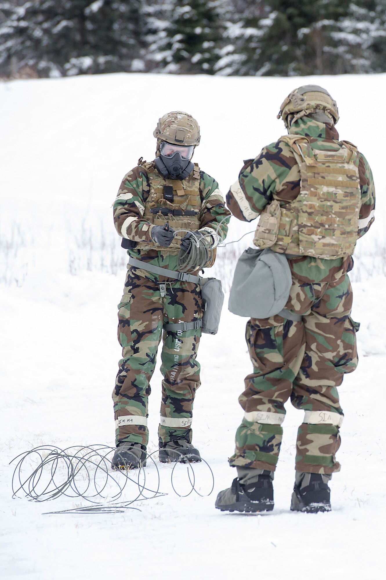 Airmen assigned to the 673d Civil Engineer Squadron, Explosives Ordinance Disposal Flight, handle detonation cord during a live-fire demolitions exercise in Mission Oriented Protective Posture 4 on Joint Base Elmendorf-Richardson, Alaska, Feb.14, 2018.  The Airmen were conducting EOD training in a simulated chemical weapons contaminated environment.