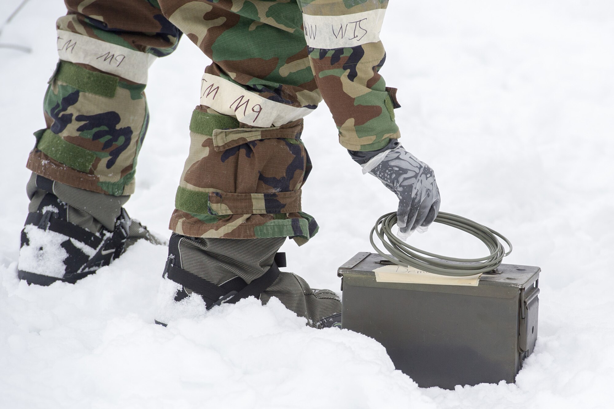 An Airman assigned to the 673d Civil Engineer Squadron, Explosives Ordinance Disposal Flight, picks up detonation cord while conducting a live-fire demolitions exercise in Mission Oriented Protective Posture 4 on Joint Base Elmendorf-Richardson, Alaska, Feb.14, 2018.  The Airmen were conducting EOD training in a simulated chemical weapons contaminated environment.