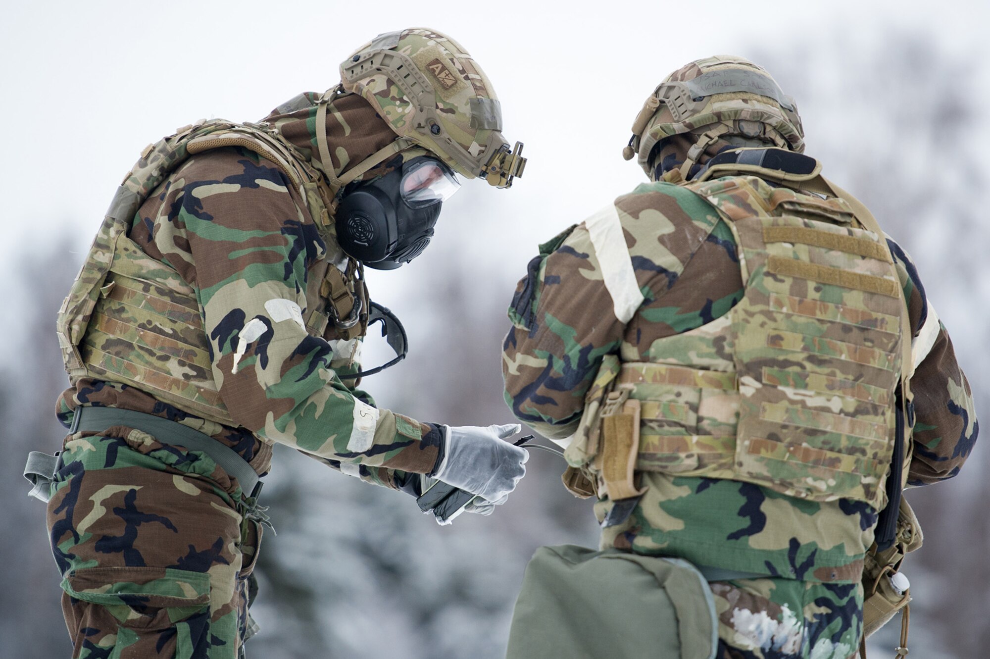 Senior Airmen Sterling Horton, left, and Michael Carlson, both assigned to the 673d Civil Engineer Squadron, Explosives Ordinance Disposal Flight, prepare a charge for a live-fire demolitions exercise in Mission Oriented Protective Posture 4 on Joint Base Elmendorf-Richardson, Alaska, Feb.14, 2018.  The Airmen were conducting EOD training in a simulated chemical weapons contaminated environment.
