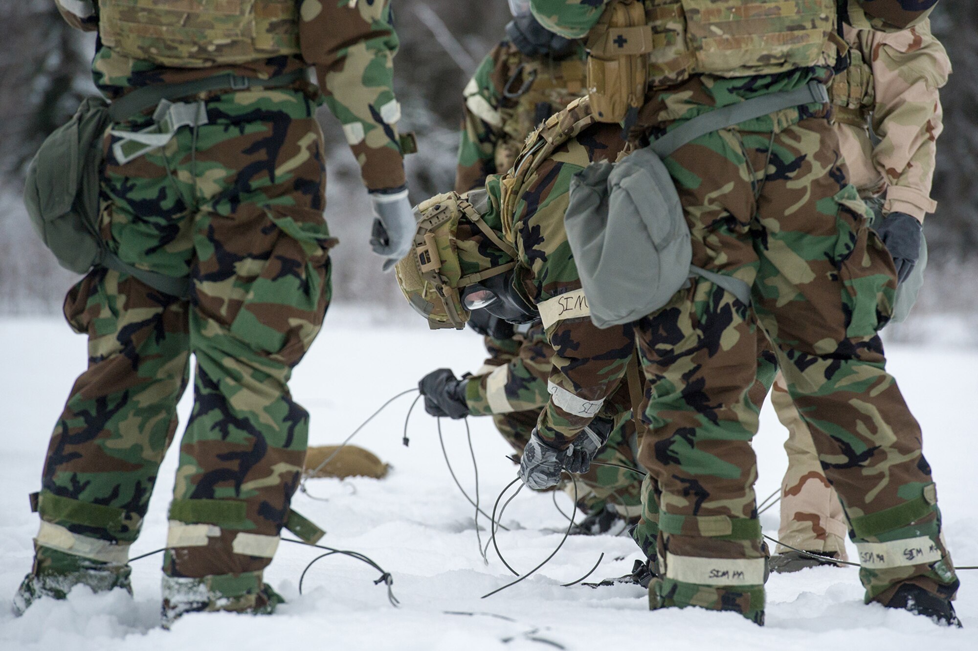 Airmen assigned to the 673d Civil Engineer Squadron, Explosives Ordinance Disposal Flight, prepare detonation cord and charges for a live-fire demolitions exercise in Mission Oriented Protective Posture 4 on Joint Base Elmendorf-Richardson, Alaska, Feb.14, 2018.  The Airmen were conducting EOD training in a simulated chemical weapons contaminated environment.