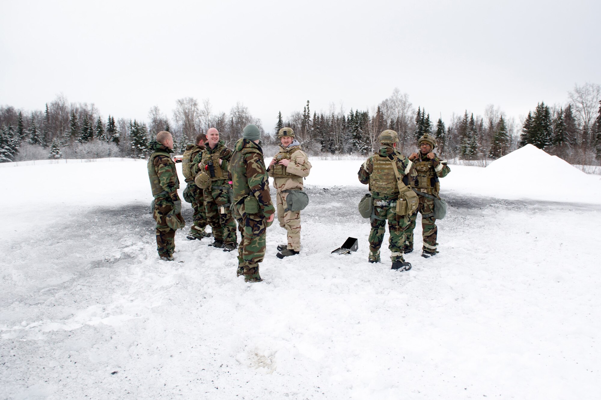 Airmen assigned to the 673d Civil Engineer Squadron, Explosives Ordinance Disposal Flight, stand near the blast area after a live-fire demolitions exercise in Mission Oriented Protective Posture 4 on Joint Base Elmendorf-Richardson, Alaska, Feb.14, 2018.  The Airmen were conducting EOD training in a simulated chemical weapons contaminated environment.