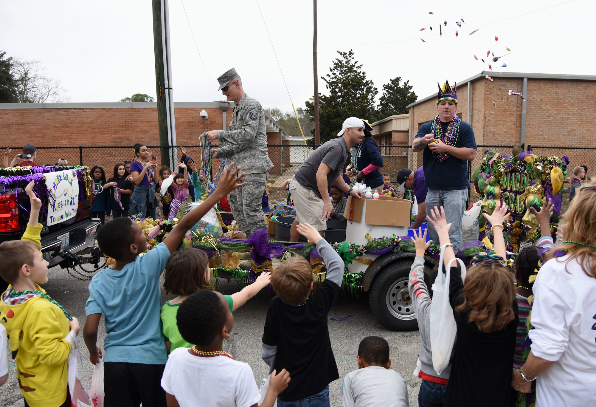 Keesler personnel toss candy and beads to children during the Jeff Davis Elementary School Mardi Gras parade Feb. 9, 2018, in Biloxi, Mississippi. Keesler leadership and other base personnel also participated in the festivities. (U.S. Air Force photo by Kemberly Groue)