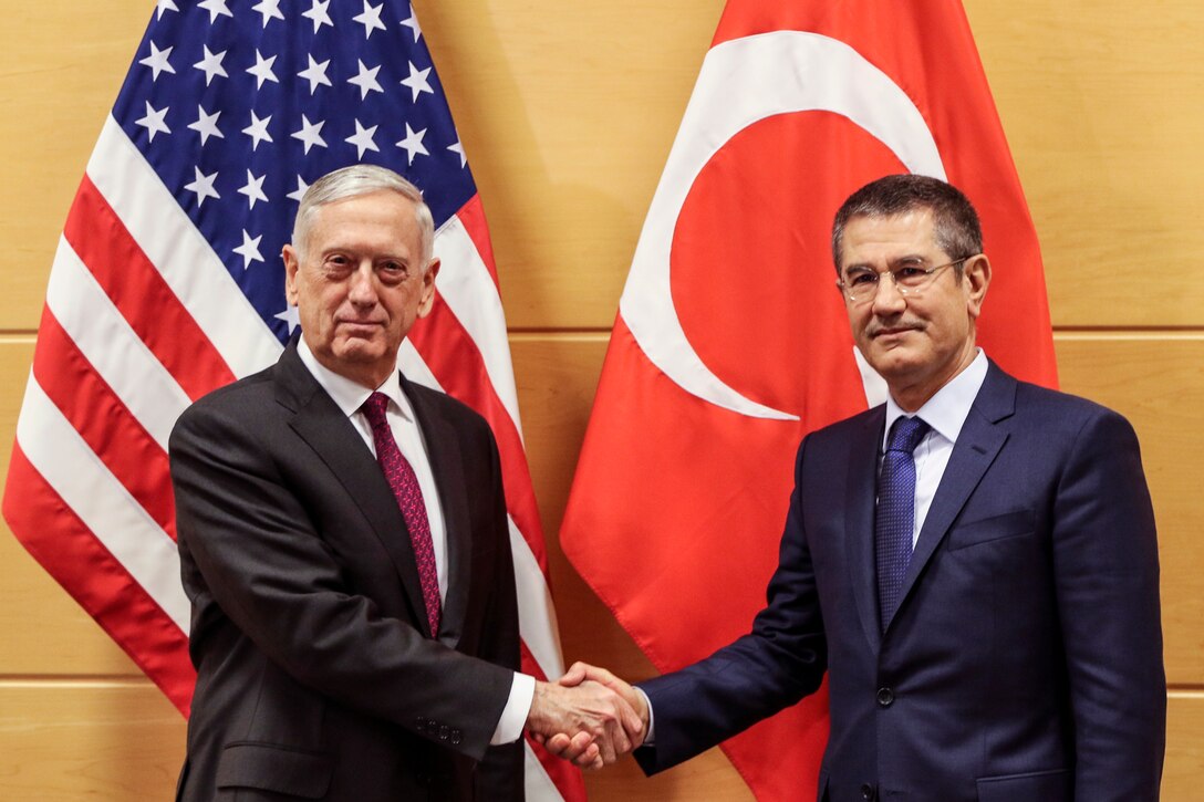 Defense Secretary James N. Mattis and his Turkish counterpart stand and shake hands in front of their nations' flags.