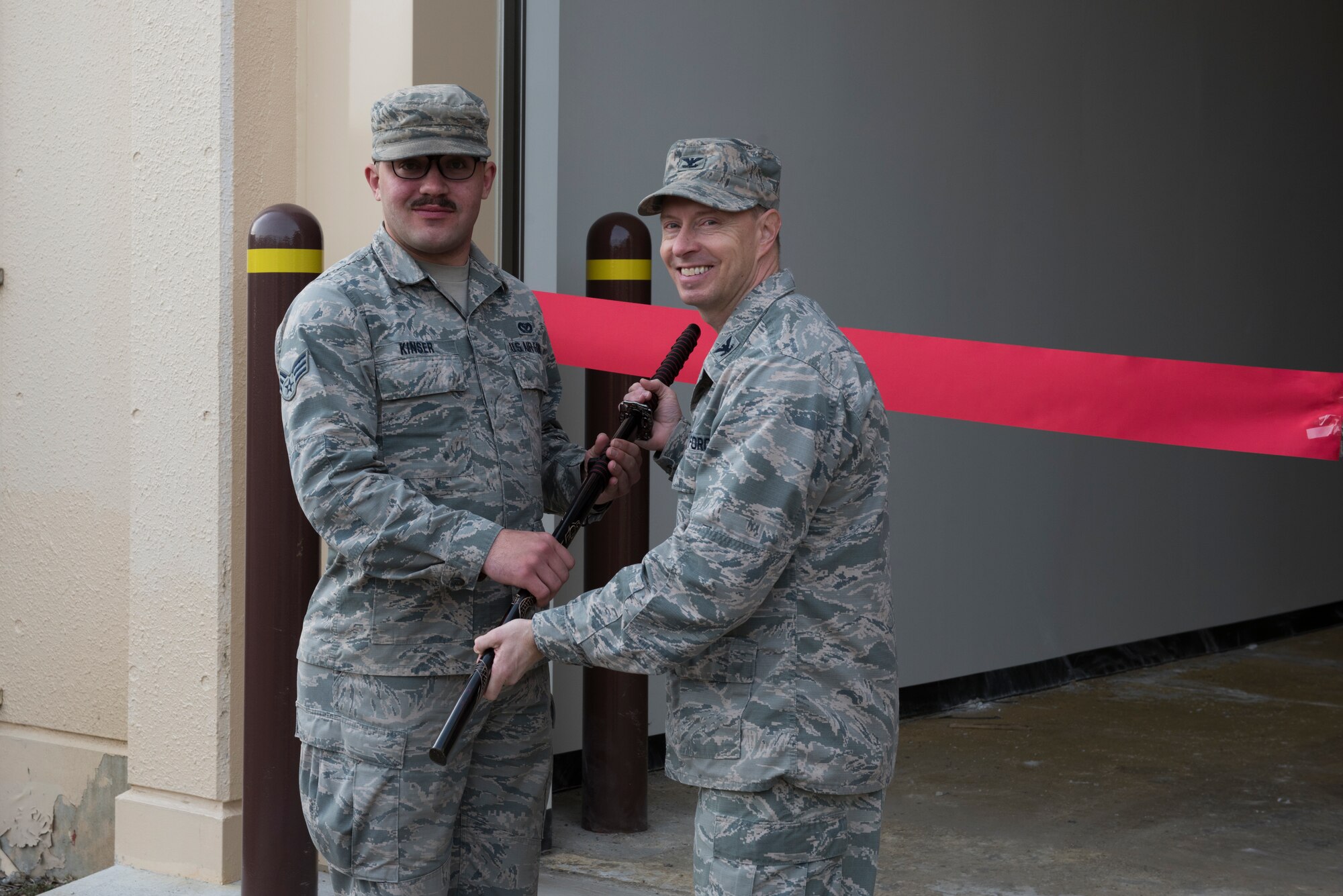Col. John Winkler, 374th Mission Support Group commander, receives a samurai sword from Senior Airman Brendan Kinser, 374th Civil Engineer Squadron pavement and equipment journeyman, to be used during the ribbon cutting ceremony for the war reserve materiel storage warehouse at Yokota Air Base, Japan, Feb. 15, 2018.