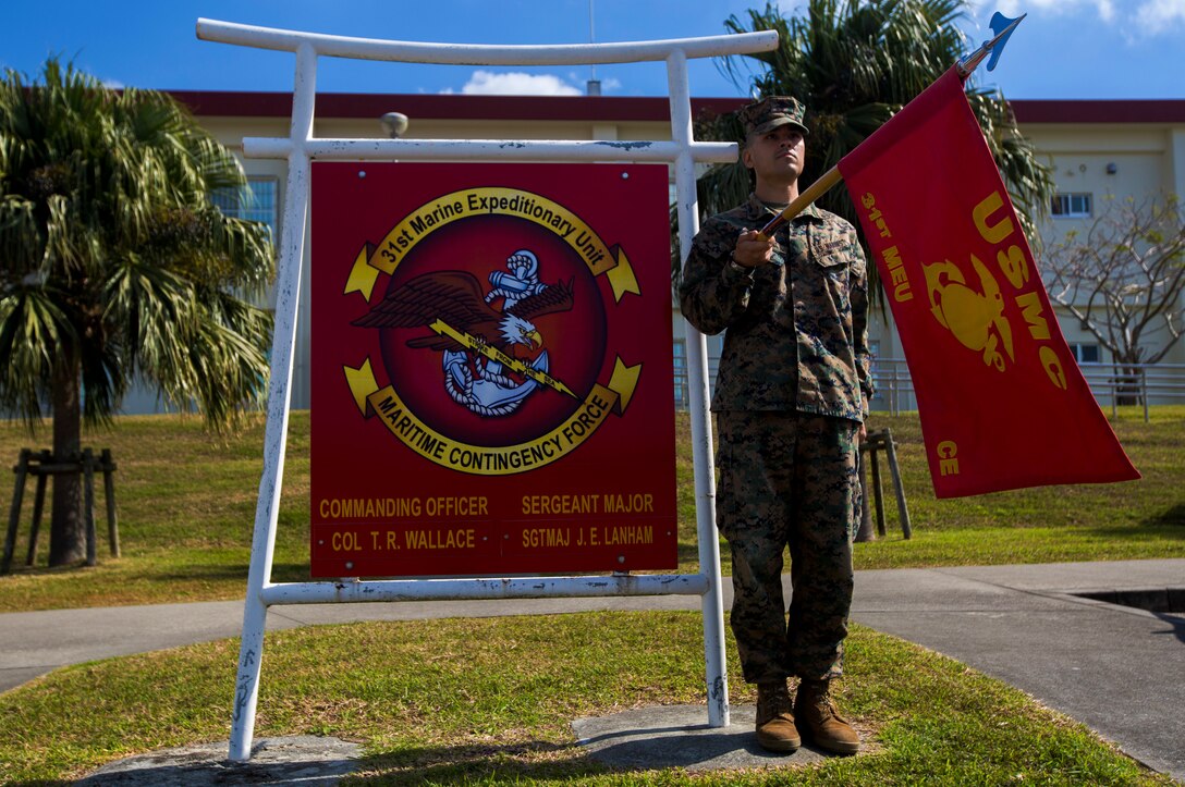 Cpl. Nicholas Rojas holds the guidon of the 31st Marine Expeditionary Unit on Feb. 13, 2018, next to Peralta Hall on Camp Hansen, Okinawa, Japan. Rojas, an administrative clerk with the 31st MEU, is a native of Chicago. As the Marine Corps’ only continuously forward-deployed MEU, the 31st MEU provides a flexible force ready to perform a wide range of military operations. (U.S. Marine Corps photo by Cpl. Andrew Neumann/Released)