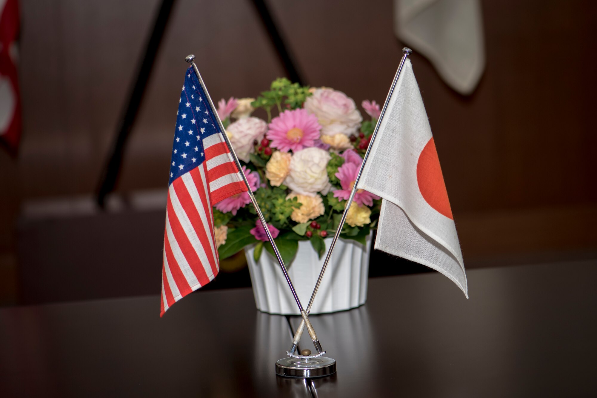 U.S. and Japan protocol flags sit next to a bundle of flowers on a table during a meeting between U.S. Air Force Master Sgt. Cesar Ventura and two Japan Air Self-Defense Force warrant officers with the 3rd Air Wing at Misawa Air Base, Japan, Feb. 14, 2018. The three met to discuss one of the warrant's retirement plans. This meeting reflects a very common theme for the three men who over the past four years have become "like family." Ventura is a vertical inspections planner with the 35th Fighter Wing's Inspector General's office and hails from Los Angeles, California. (U.S. Air Force photo by Tech. Sgt. Benjamin W. Stratton)