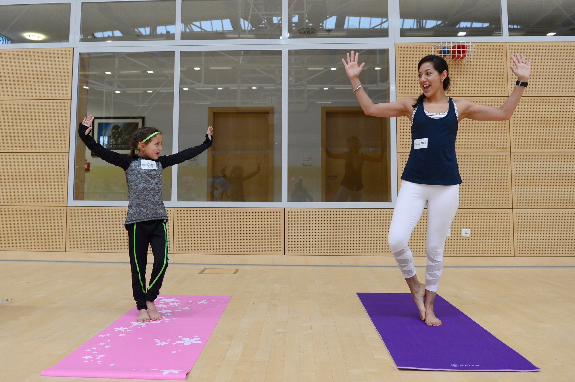 Capt. Laura Pfledderer, 52nd Medical Operations Squadron social worker, and her daughter Isabella, showcase their yoga skills during Fit Family Fun Day at the PowerHaus Fitness Center at Spangdahlem Air Base, Germany, Feb. 10, 2018. Pfledderer and her daughter led a beginner’s yoga class during the event to teach various relaxation techniques. (U.S. Air Force photo by Airman 1st Class Jovante Johnson)
