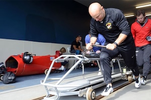 A soldier pushes a modified bobsled.