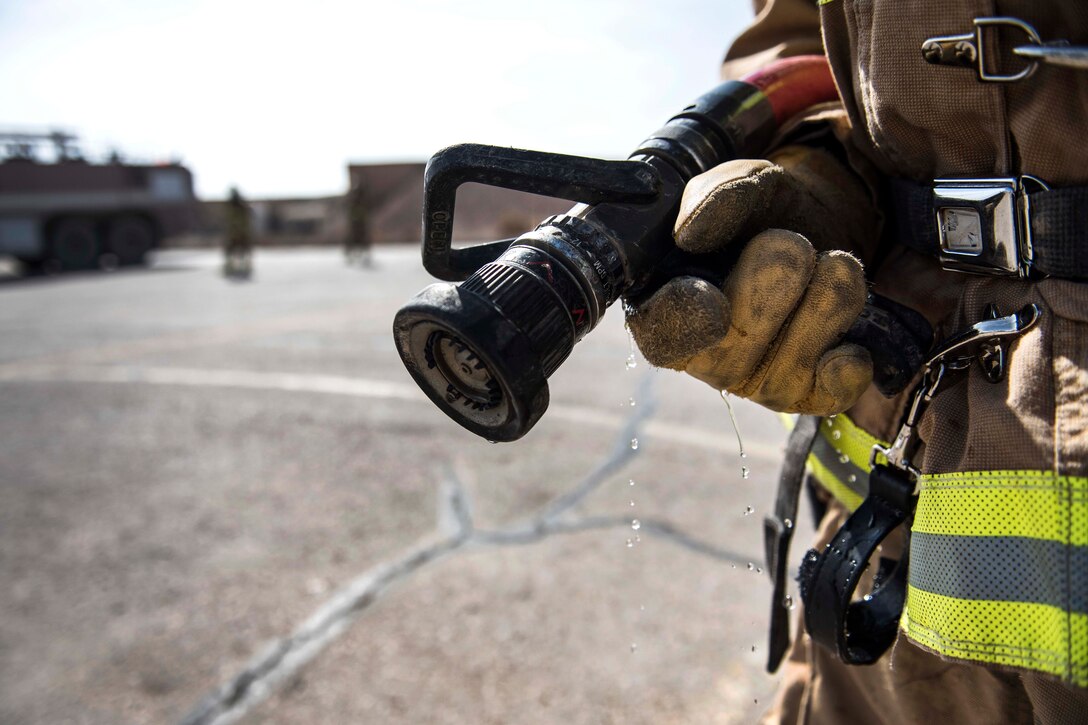 An Air Force firefighter holds a firehose while participating in an emergency aircraft egress training.