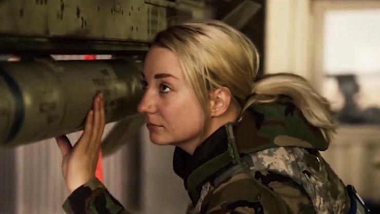 A service member gazes at a piece of equipment she is handling.