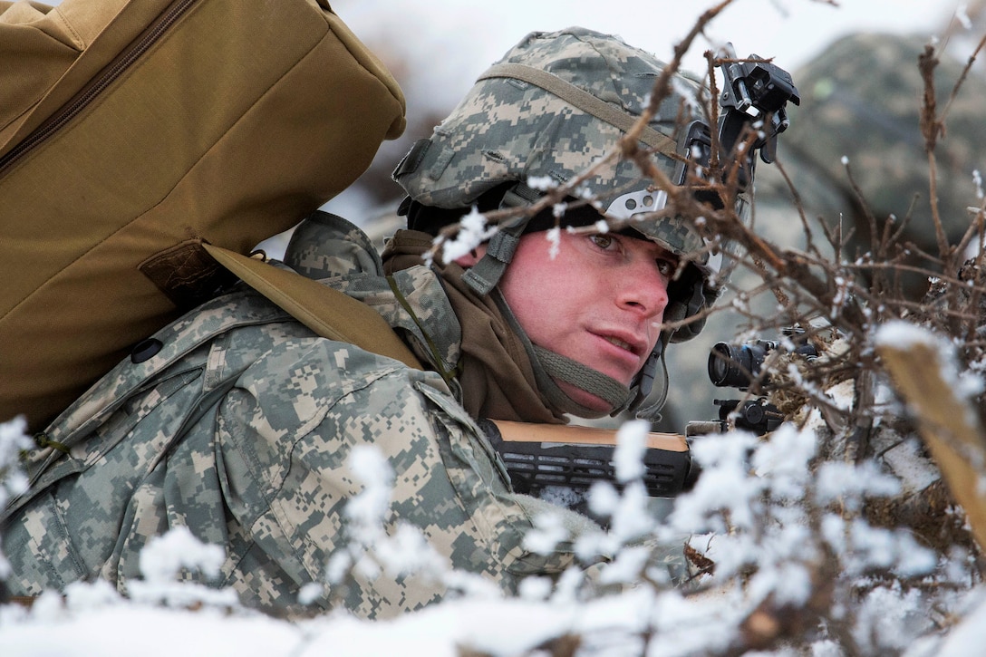 A soldier takes cover while waiting to advance.