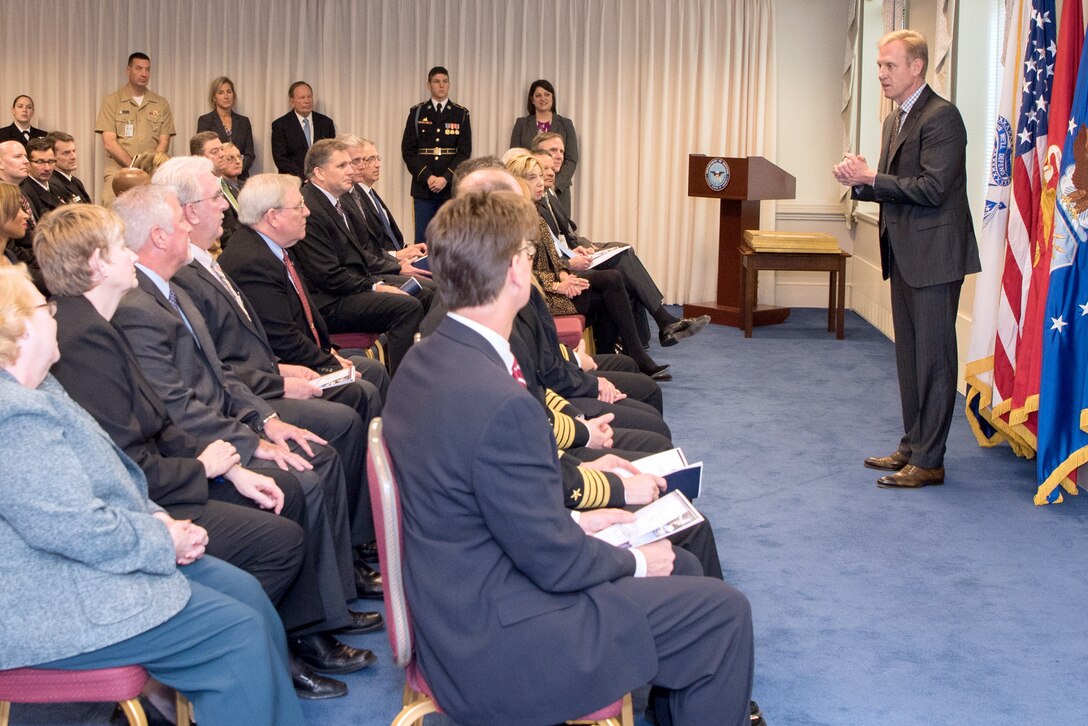 The deputy defense secretary stands speaks to a group of people.