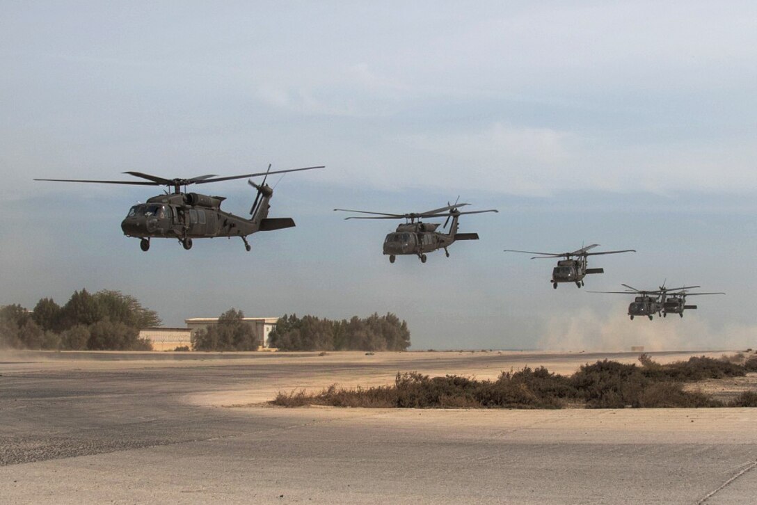 Five Army UH-60 Black Hawk helicopters take off in unison.