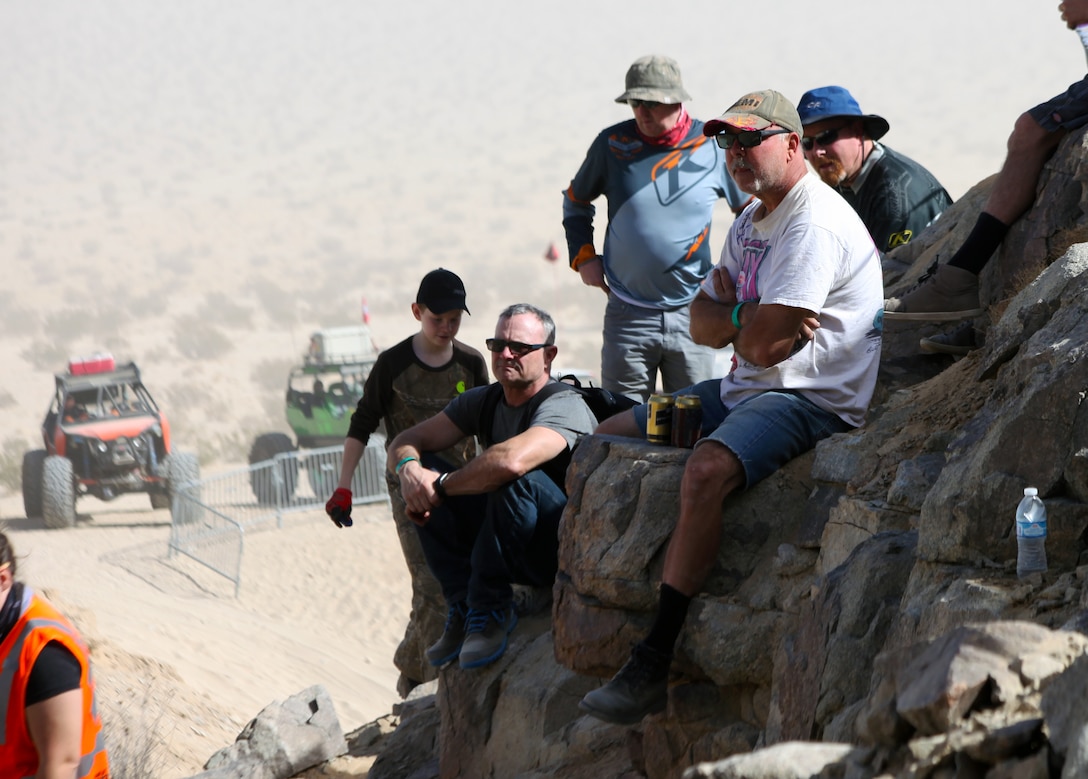 Spectators perch on a rock outcropping to watch a King of the Hammers attendees crawl up Back Door, Feb. 5, 2018. The challenging climb filled with rocks and deep craters is one of many that participants take on during KOH, the largest racing and rock-crawling event in North America. (Marine Corps photo by Kelly O’Sullivan)