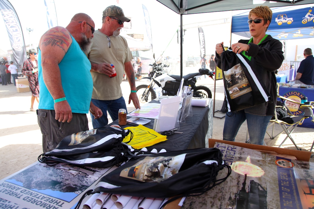 Marine Corps Air Ground Combat Center Land Manager Jonell Kosa talks to visitors at the Government and External Affairs booth in Johnson Valley, Calif., Feb. 7, 2018, about educational and outreach products available to them. King of the Hammers is the largest off-road racing and rock-crawling event in North America. GEA handed out more than 1,700 products in Hammertown over a three-day period. (Marine Corps photo by Kelly O’Sullivan)