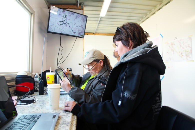 Katrina Symons, left, field manager, Bureau of Land Management Barstow, Calif., field office, and Kristina Becker, deputy director, Marine Corps Air Ground Combat Center Government and External Affairs, monitor the Can-Am KOH UTV Race in the King of the Hammers operations trailer in Johnson Valley, Calif., Feb. 7, 2018. Multiple federal, state and county agencies work together with race organizer HammerKing Productions during King of the Hammers, the largest off-road racing and rock-crawling event in North America. (Marine Corps photo by Kelly O’Sullivan)