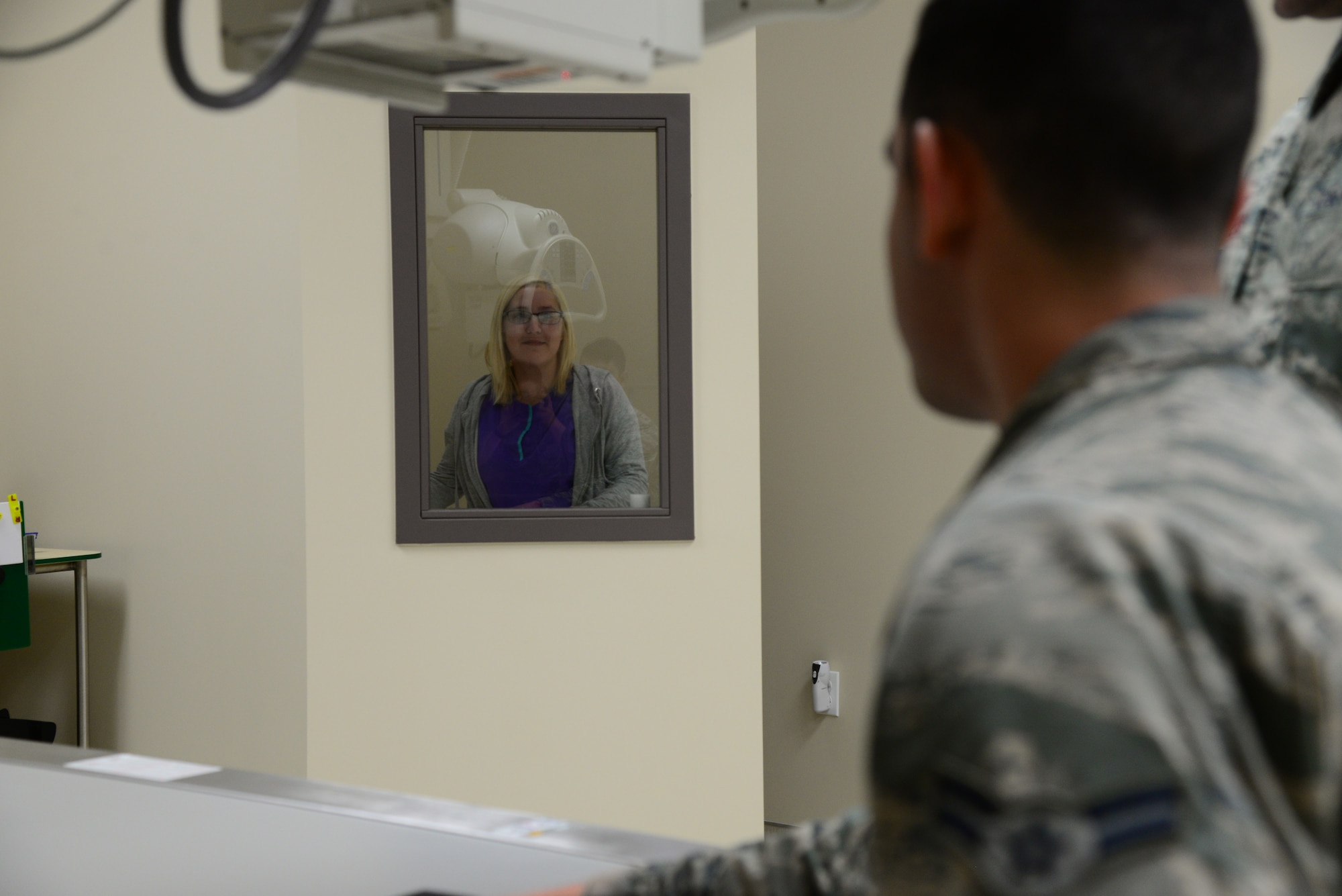 Torrie Gates, 14th Medical Support Squadron radiologic technologist, stands behind a wall while Airman 1st Class Michael Mannarino, 14th Medical Operations Squadron bioenvironmental engineer apprentice, simulates getting an X-ray Feb. 14, 2018, on Columbus Air Force Base, Mississippi. The Kortiz Clinic radiology department’s primary mission is patient care which saves the Airmen time and trouble by getting quicker results. (U.S Air Force photo by Airman 1st Class Beaux Hebert)