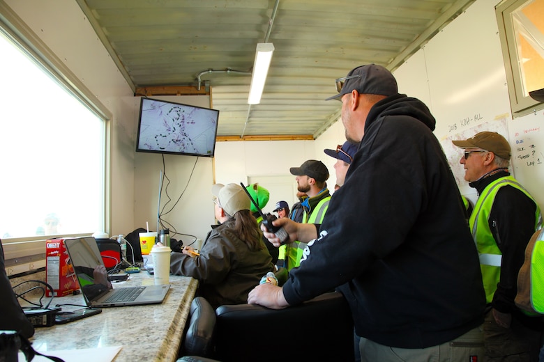 King of the Hammers co-founder Dave Cole, foreground, and members of the media watch Can-Am KOH UTV Race progress on a monitor in the race event’s operations trailer with Katrina Symons, field manager, Bureau of Land Management Barstow, Calif., field office, Feb. 7, 2018. King of the Hammers is the largest off-road racing and rock-crawling event in North America. (Marine Corps photo by Kelly O’Sullivan)
