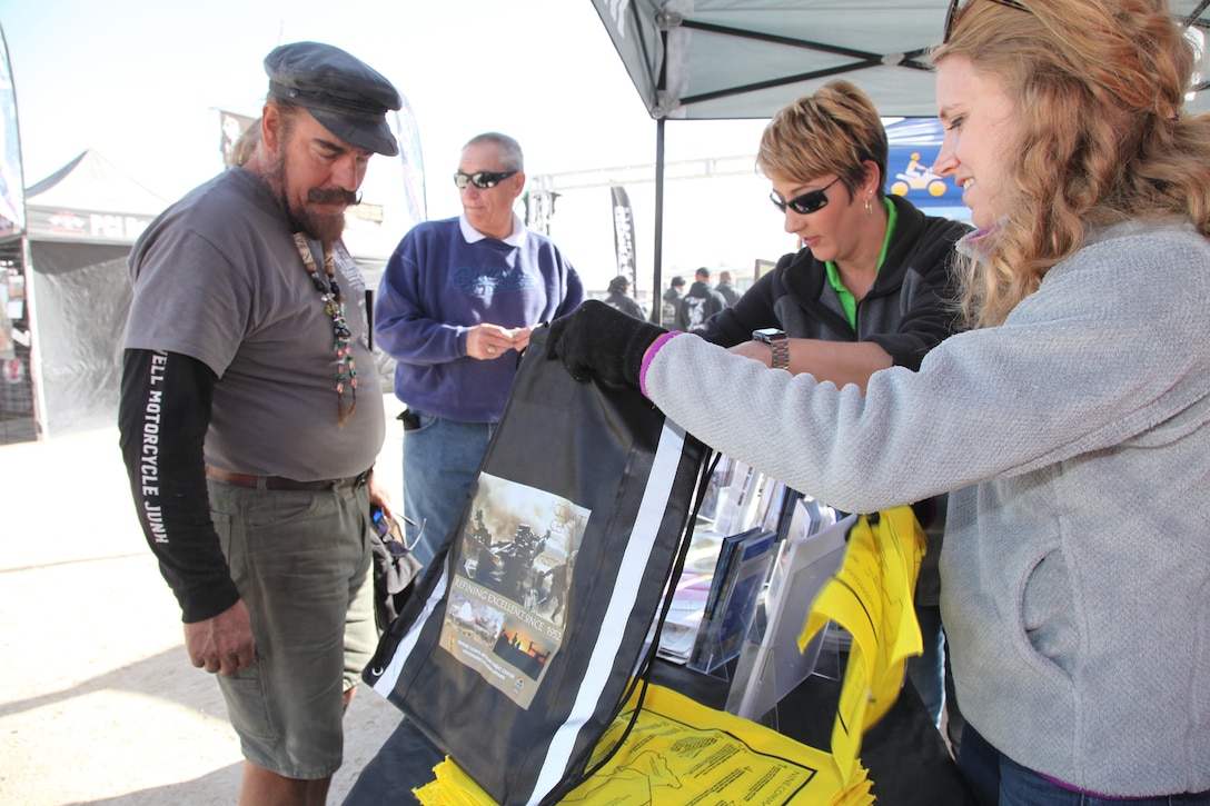 Marine Corps Air Ground Combat Center Land Manager Jonell Kosa, center, and Julie McLean, communications and logistics specialist, provide a King of the Hammers attendee with educational outreach products at the Government and External Affairs booth in Johnson Valley, Calif., Feb. 7, 2018. King of the Hammers is the largest off-road racing and rock-crawling event in North America. GEA handed out more than 1,700 products in Hammertown over a three-day period. (Marine Corps photo by Kelly O’Sullivan)