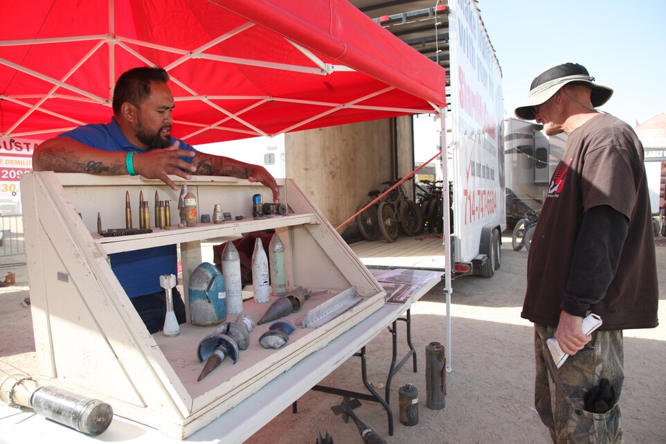 Palani Paahana, left, Marine Corps Air Ground Combat Center Range Sustainment Branch, talks about ordnance used in military training on the base with a visitor to the Combat Center’s static display outreach booth at King of the Hammers in Johnson Valley, Feb. 7, 2018. King of the Hammers is King of the Hammers is the largest off-road racing and rock-crawling event in North America. (Marine Corps photo by Kelly O’Sullivan)