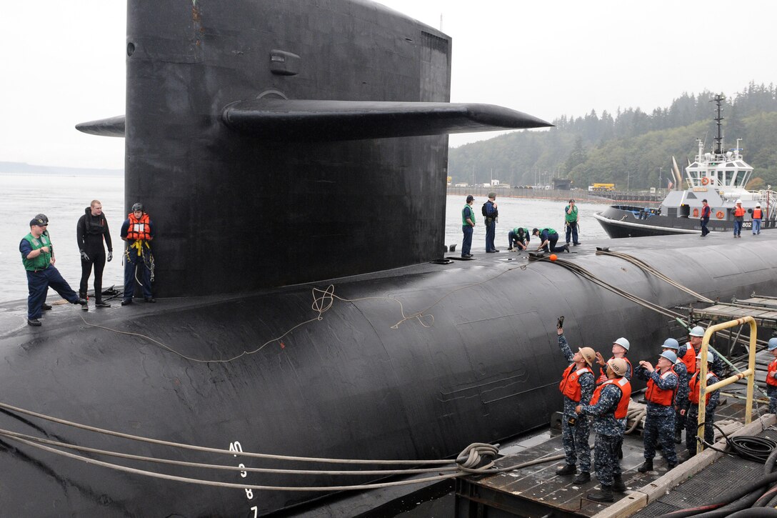 Sailors tie a submarine to a pier.