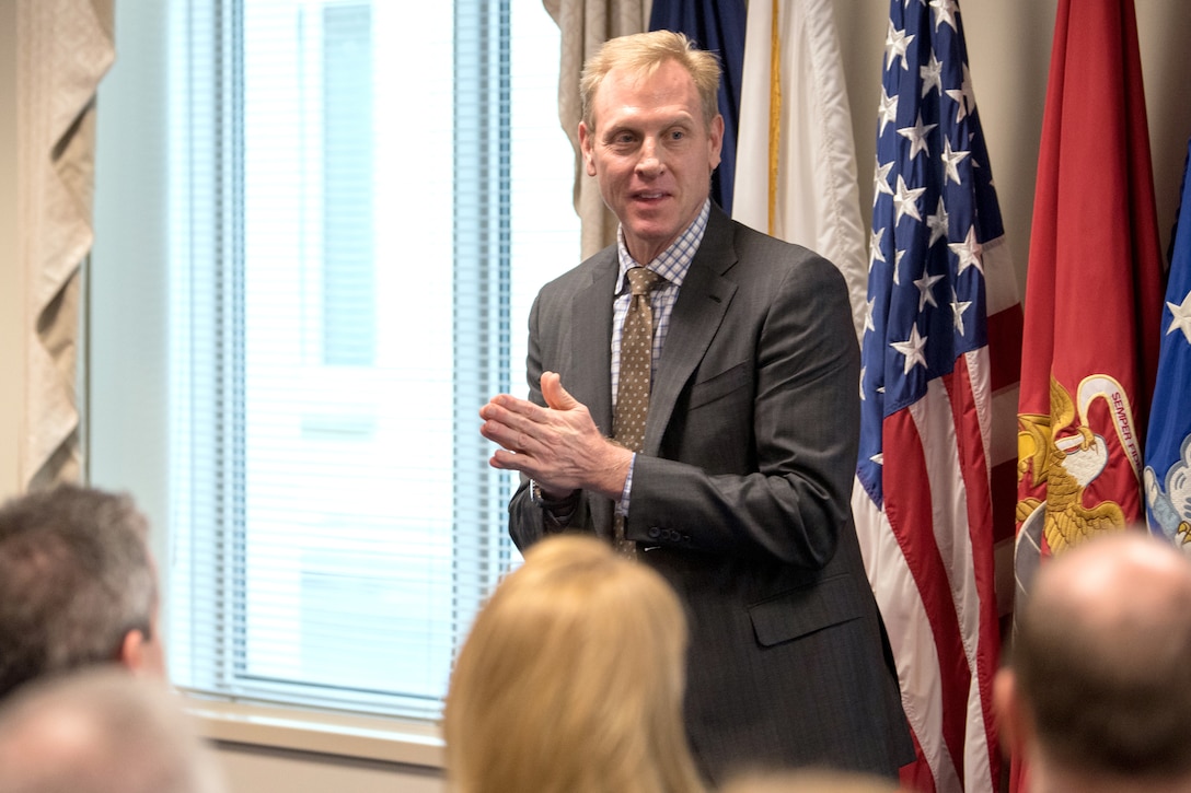 The deputy defense secretary stands speaks to a group of people.